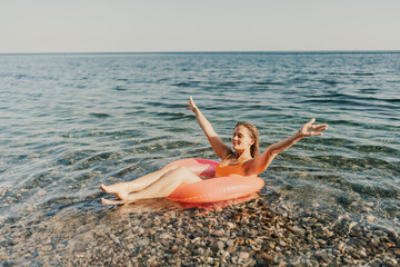 A woman is floating in a red inflatable tube in the ocean