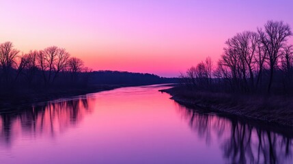 Obraz premium A calm river reflecting the soft pink and purple hues of an autumn sunset. The minimalist composition features gently flowing water and bare trees silhouetted against the colorful sky. --