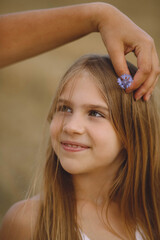 Fototapeta premium Mother holding wild flower near hair of her daughter outdoor