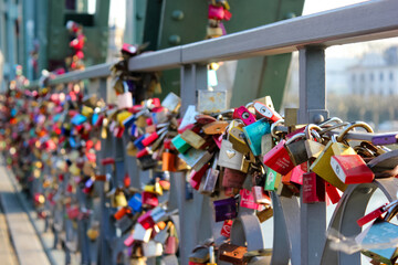 A close-up of countless colorful padlocks attached to a bridge's railing symbolizing love and...