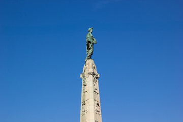 Statue on a tall monument with clear blue sky background, symbolizing victory and remembrance, perfect for Memorial Day content