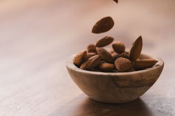 peeled almonds falling in wood bowl with copy space