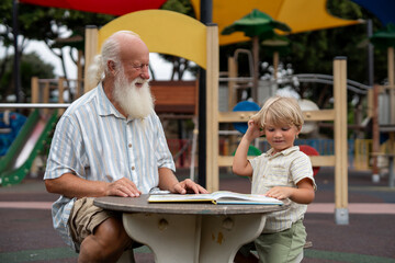 Grandfather with White Beard Sharing a Joyful Moment with Grandson at Colorful Playground Table