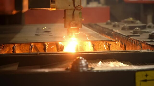 Plasma laser cutter automated machine cuts through a sheet of metal on plant. Power accuracy of laser beam highlight laser engraving marking shape in metalworking. Metal industry production process.