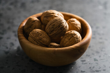 inshell walnuts in olive wood bowl on terrazzo countertop