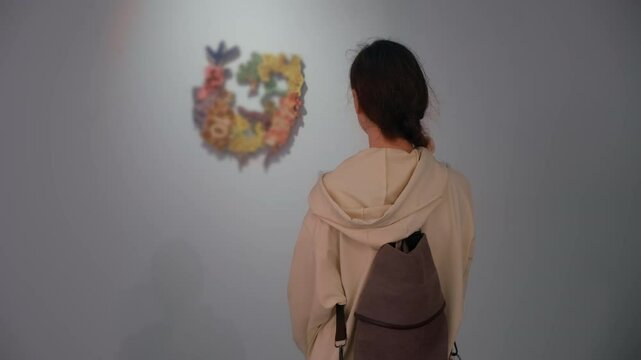 Woman admiring looking at art object in museum standing back to exhibit on excursion. Modern creative exhibition.