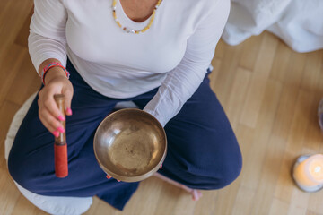 Young woman playing on a singing tibetian bowl.Relaxation and meditation.Sound therapy,alternative medicine.top view