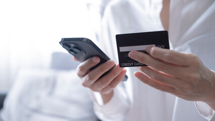 Close up female hands holding credit card and smartphone, young woman paying online, using banking service, entering information, shopping, ordering in internet store, doing secure payment