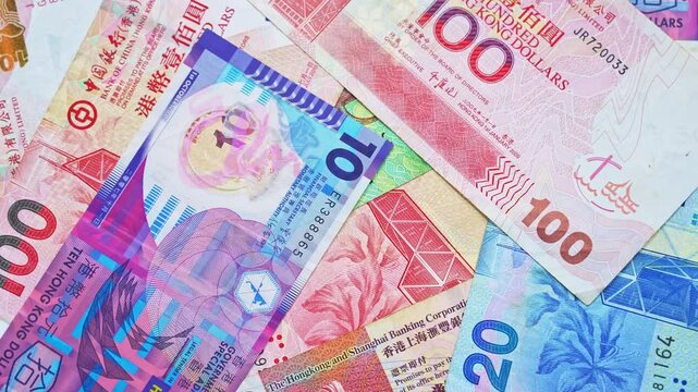 Falling Hong Kong dollars banknotes and pile of Hong Kong currency banknotes are spinning on table