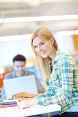 Education, portrait and writing on notebook in classroom for study group, project or assignment. Female person, smile and pencil for student, course or learning in college, campus or university in UK