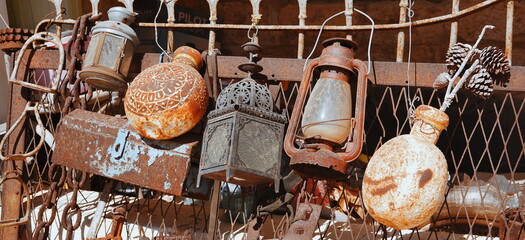 Collection of old utensils. Rust and peeling paint. Lanterns and flags are hanging on the fence. A...