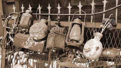 Collection of old utensils. Rust and peeling paint. Lanterns and flags are hanging on the fence....