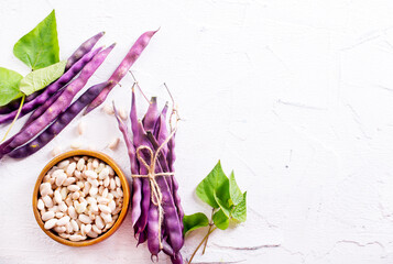 Uncooked dried white haricot beans in bowl n on table. Heap of legume haricot bean background