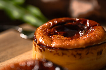 バスクチーズケーキのクローズアップ。焦げ目が美しい質感を引き立てる甘い焼き菓子のディテールが、自然光と室内撮影で表現されています。