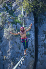 A tightrope walker walks along a cable stretched over a canyon.
