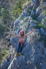 A tightrope walker walks along a cable stretched over a canyon.