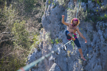 A tightrope walker walks along a cable stretched over a canyon.