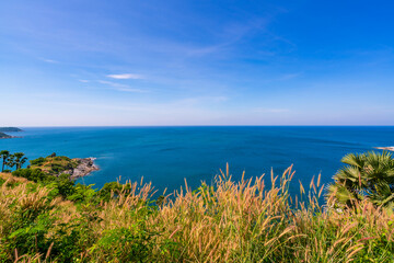 Laem promthep cape with coconut palm trees and grass in the foreground beautiful scenery andaman sea in summer season Phuket thailand Beautiful travel background