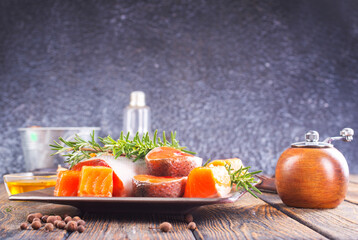 Salmon. Fresh raw salmon fish fillet with cooking ingredients, herbs and lemon on dark background
