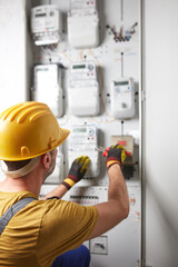 Technician working on a modern electricity power meter station in a building.