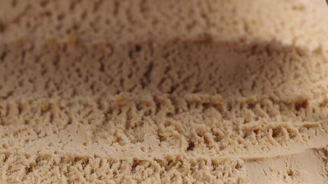 Slow motion closeup hazelnut praline ice cream scooping with spoon