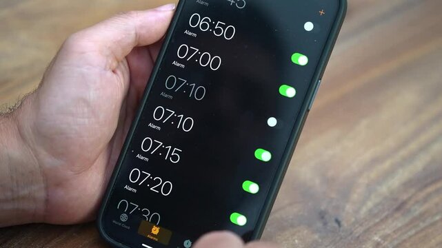 Fitness enthusiast sets alarm on smartphone sitting at table planning early morning workout routine to maintain physical fitness and achieve personal health goals