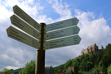 Wegweiser von Wanderwegen, unter anderem des Premium-Wanderwegs Nat'Our Route 5 am Fuße der Burg Vianden in Luxemburg. 