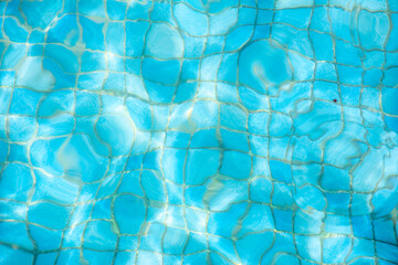 Blue water surface viewed from above in outdoor swimming pool, sun reflection. Abstract surface water background, summer holidays concept