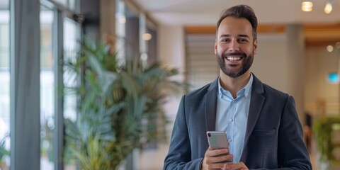 Male professional holding a mobile phone in an office
