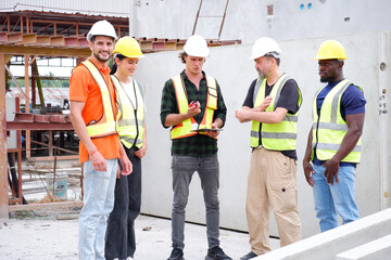 Male and female engineers stand in a planning meeting at a construction site.