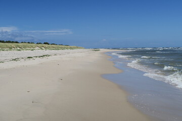 An diesem sonnigen Sommertag branden Wellen an einem ruhigen Abschnitts des Strands Sandhammaren in Ystad in der schwedischen Provinz Schonen. Der Strand wird von einem Dünengürtel begrenzt.