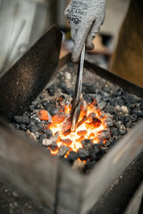 a blacksmith working in a furnace, closeup, ambers