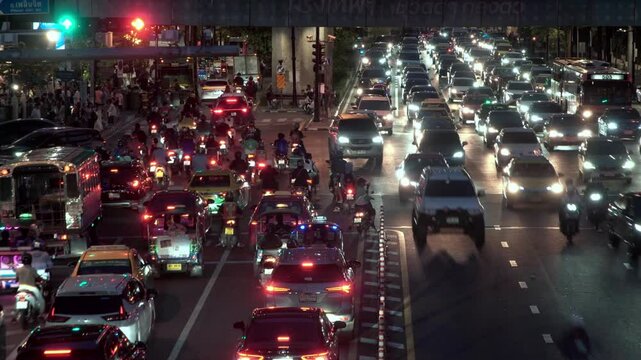 Timelapse of night traffic jam in Bangkok, Thailand, during rush hour in downtown. Capturing the motion of car tail lights and red stop signals, with vehicles moving through the cityscape. Showcasing	