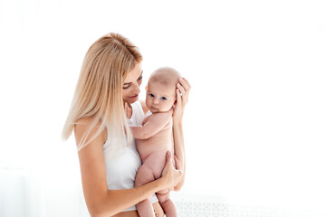 mom and baby hug and kiss, a young mother gently hugs a newborn baby girl holding her in her arms, maternal love and care, a young family, mother and daughter, a place for text