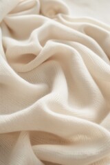 White fabric with subtle wavy texture folded in half reveals intricate pattern. Fabric appears smooth and natural with slight wrinkles. Background blurred to focus on fabric details.
