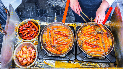 A young Basque farmer (Baserritarra) roasting Txistorra (fresh chorizo) to prepare Talos, a traditional street food served during the Day of Saint Thomas.