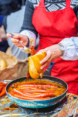 A Basque farmer (Baserritarra) frying Txistorra (fresh chorizo) to prepare Bocadillo de Txistorra, a traditional street food served during the Day of Saint Thomas.
