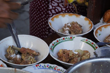 A street food vendor in Surabaya, Indonesia, is adding cooked beef ribs to bowls of soup.