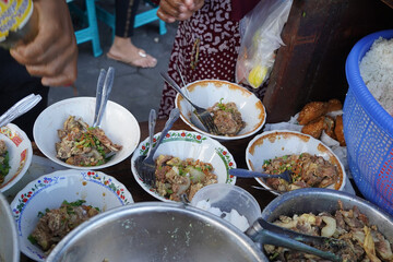 A street food vendor in Surabaya, Indonesia, is adding cooked beef ribs to bowls of soup.