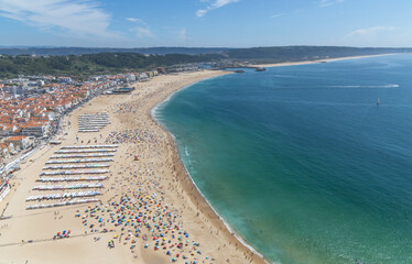 Panorama of Nazar&eacute; atlantic ocean, beach,  on a summer day with a beach full of people at Nazare Portugal.
