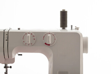 Part of a sewing machine with a black spool of thread against a white wall. Tailoring service concept. Copy space for text, automatical