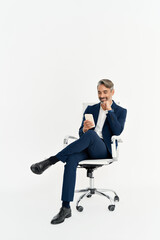Happy middle aged business man using phone sitting in office chair isolated on white background....