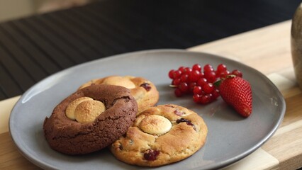 Biscuits on sleek grey plate bring touch of modern elegance. Fresh berries add a vibrant pop of color, while warm cup of eco-friendly tea completes this stylish and naturally inviting breakfast.