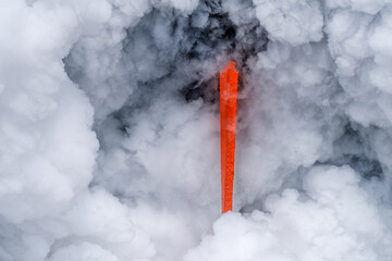 Lava tube flowing into ocean in Hawaii at dawn shows the poisonous steam rising as the hot liquid...