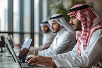 Group of Arab businessmen in traditional clothes having a meeting using laptops to work in a modern building