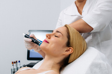 A woman receives a hydrofascial facial treatment in a modern clinic, focusing on advanced skin rejuvenation techniques and contemporary skincare practices.