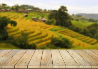 Wooden table top on blur rice field background in daytime.Harvest rice or whole wheat.For montage product display or design key visual layout.View of copy space.