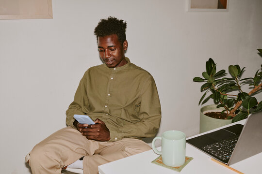 Black man chatting in social network while having break in cozy office