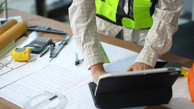 Architects or engineer holding pen pointing equipment architects on laptop with on on architectural project at construction site at desk in office.
