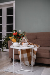 A Cozy Living Room Featuring a Soft Blanket, Lush Green Plants, and a Warm Cup of Coffee